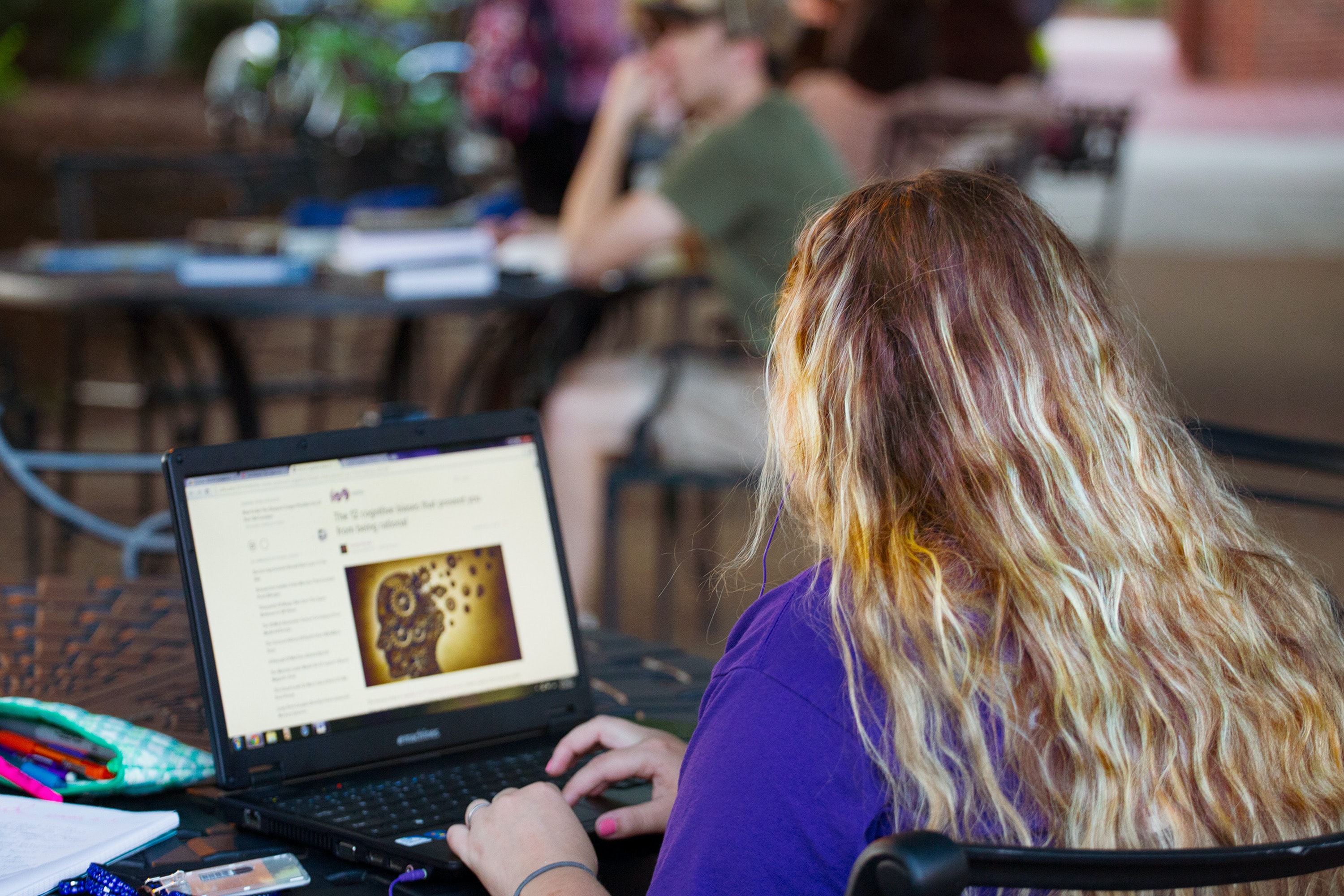 A woman sat at a table researches a topic.
