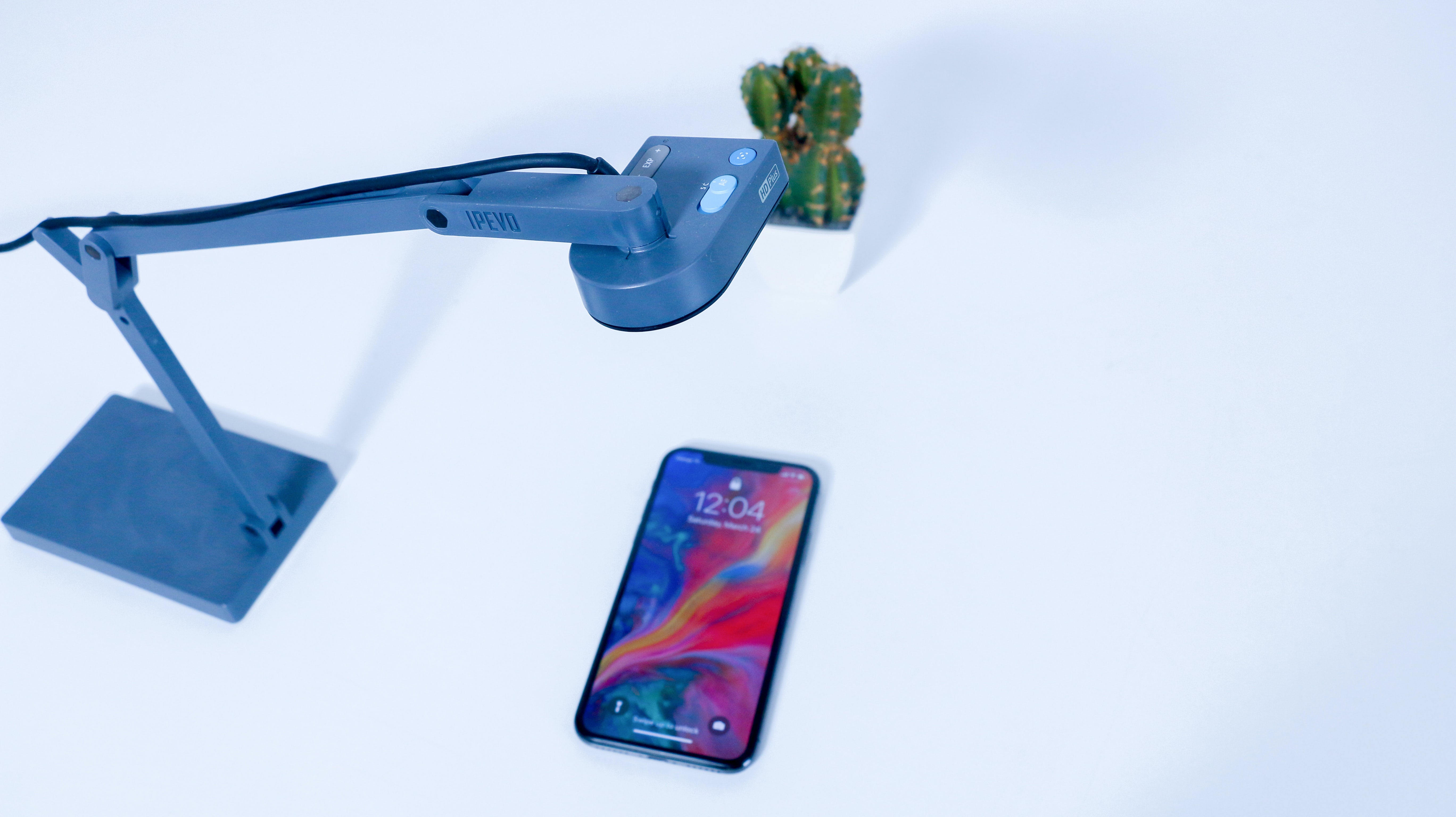 An iPhone is set up underneath a remote webcam for user testing. Behind the camera and the iPhone is a little succulent plant.