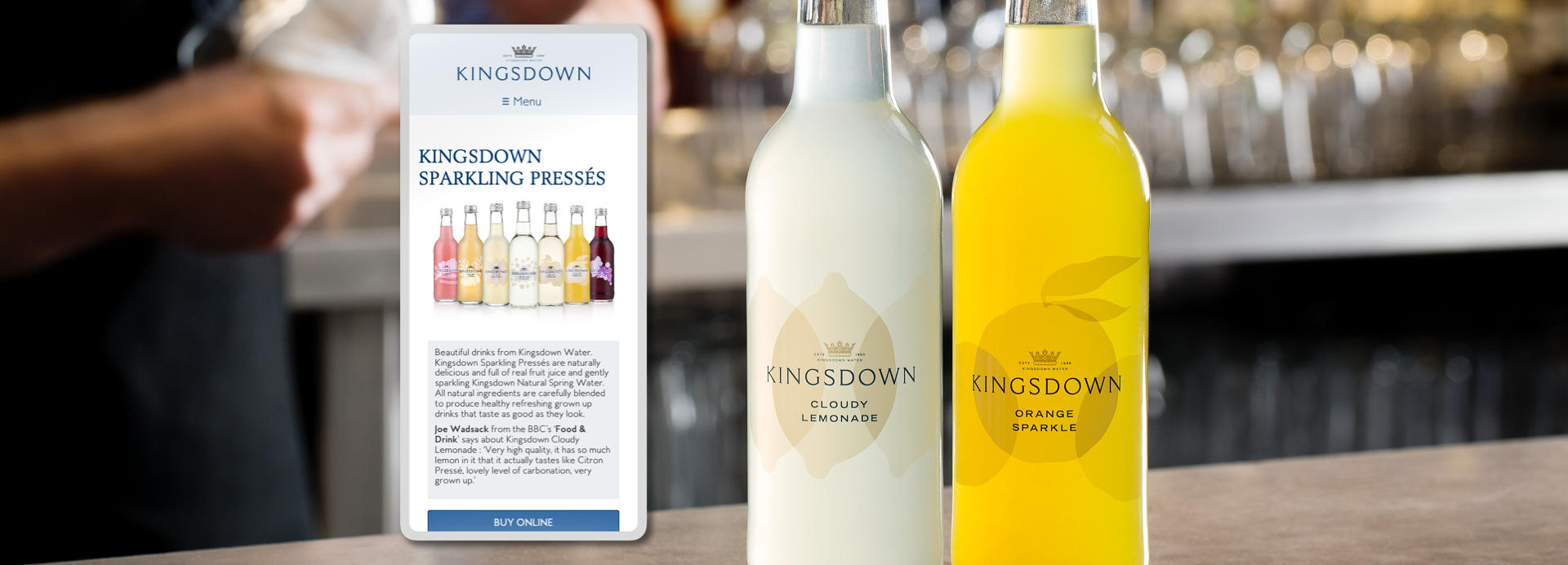 A bar scene with a smartphone showing the Kingsdown Water website next to a selection of KW drinks on the bar.