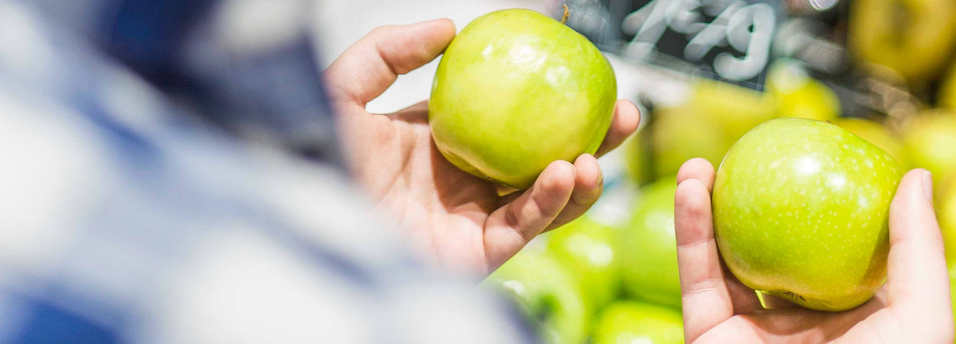 Man holding two green apples and trying to choose between them