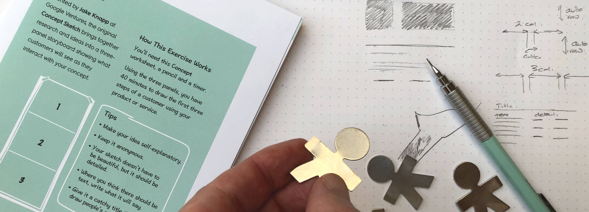 Pencil diagrams, Sprinty branded exercise sheets and a hand holding person shaped metal cutouts